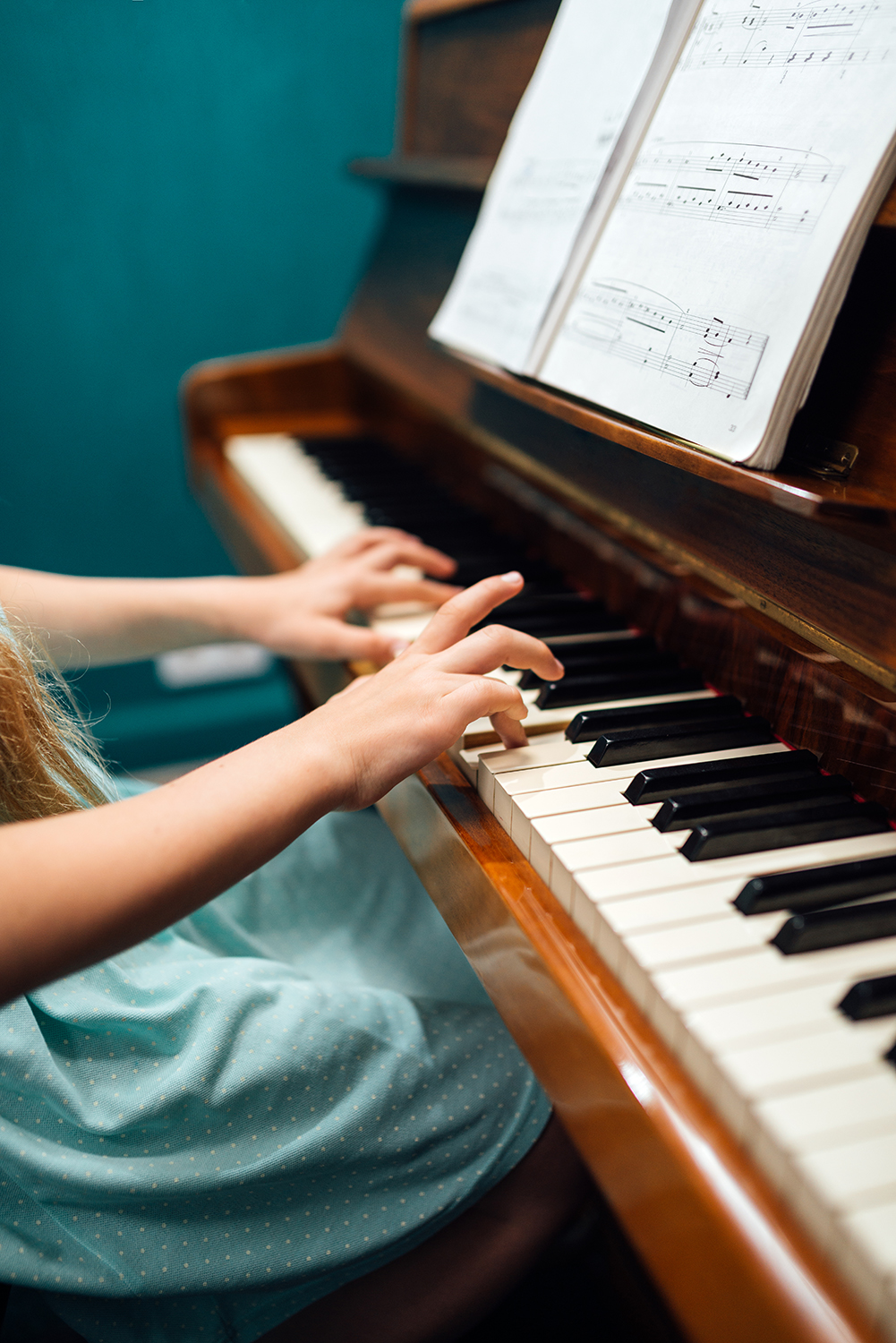 Girl music school student playing the piano with notes, side view