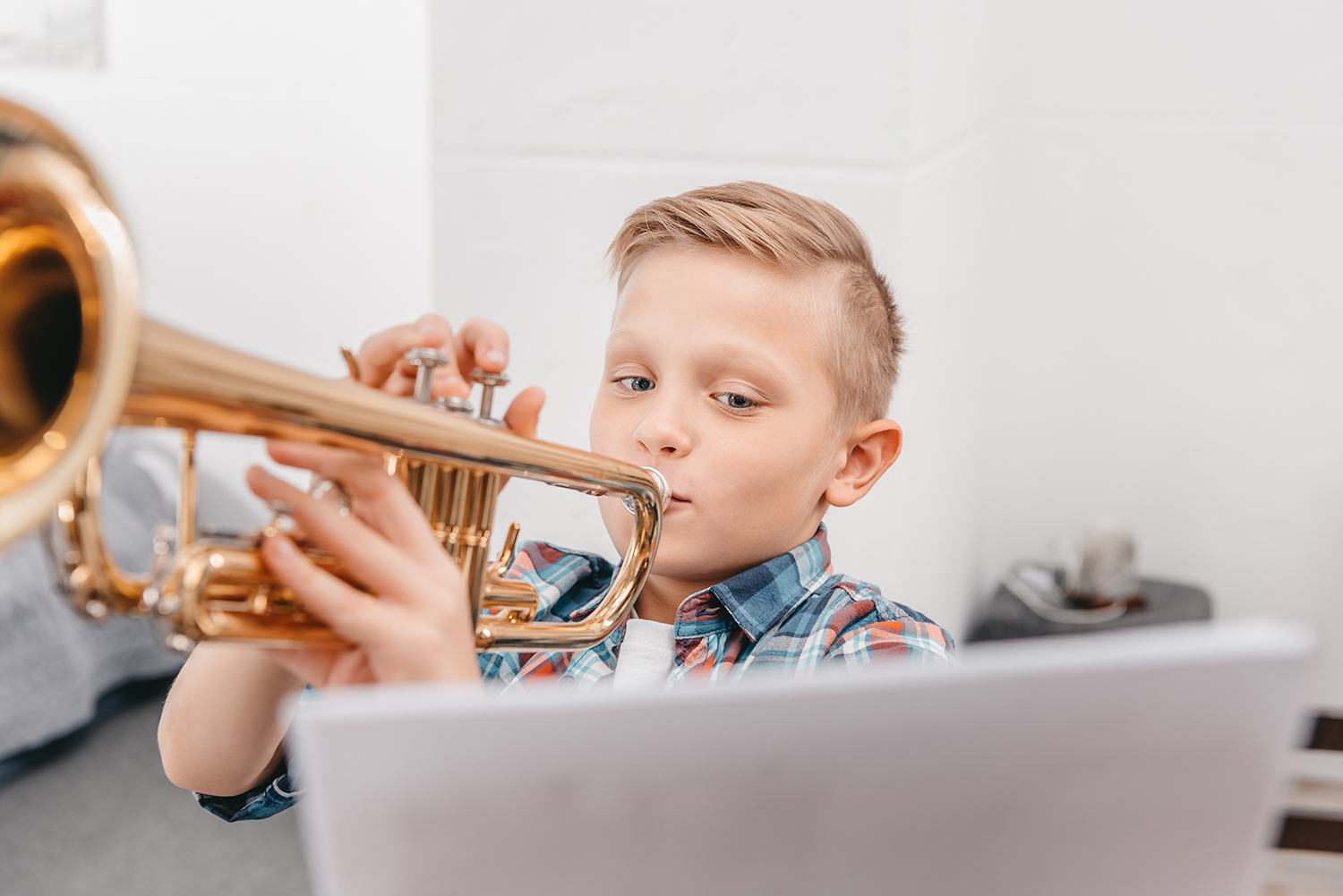 Young boy practicing playing trumpet in living room at home