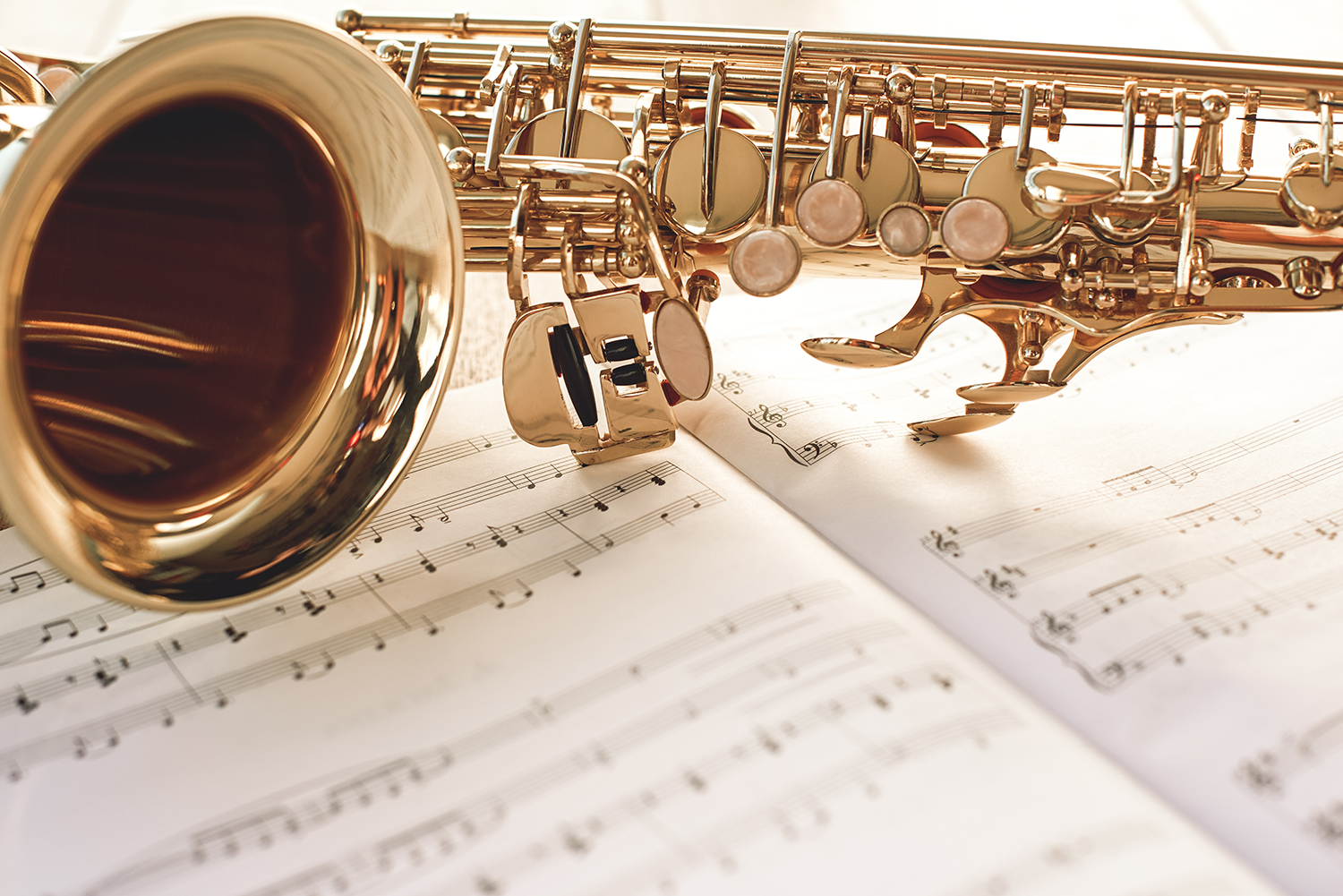 Closeup of a beautiful and shiny golden saxophone lying on music notes. Musical instruments. Music equipment.