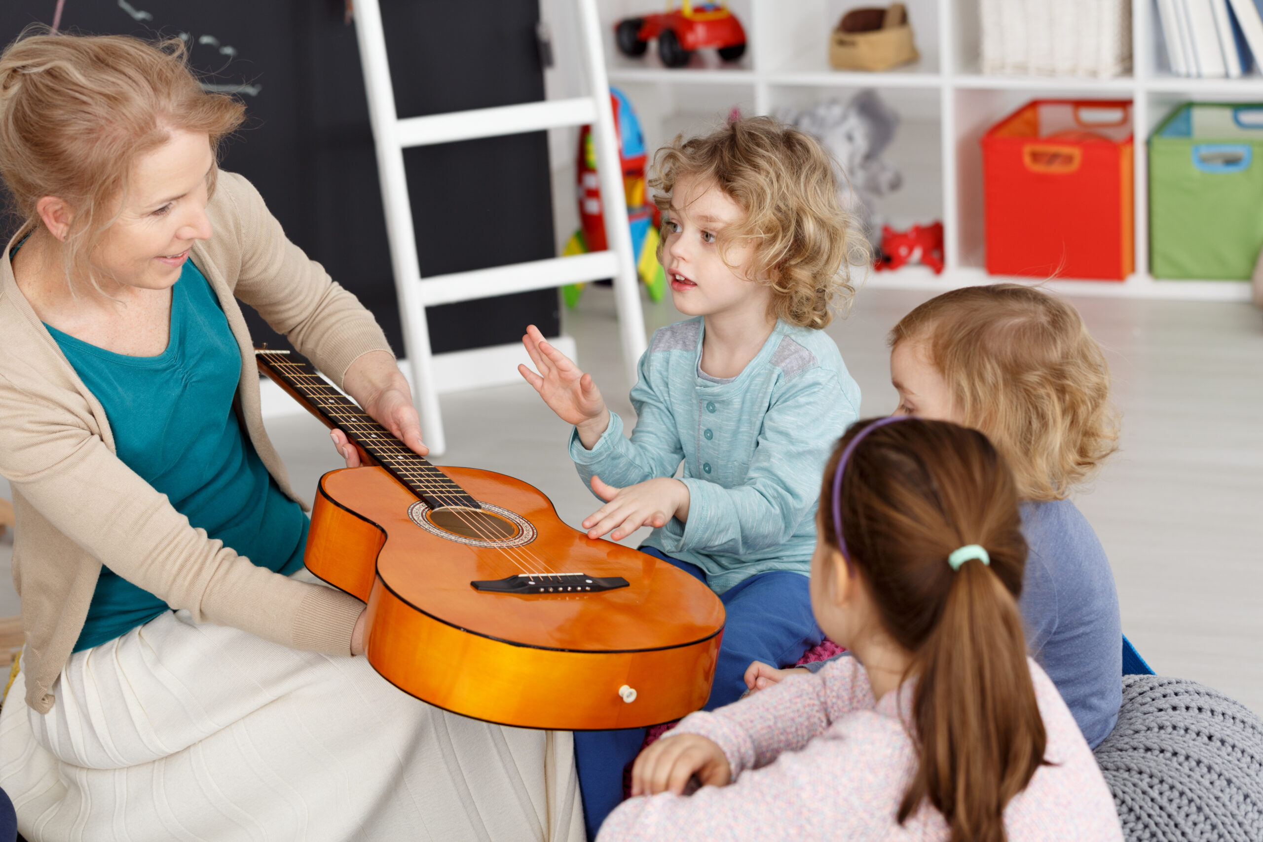 Young teacher having music lesson with small kids in kindergarten